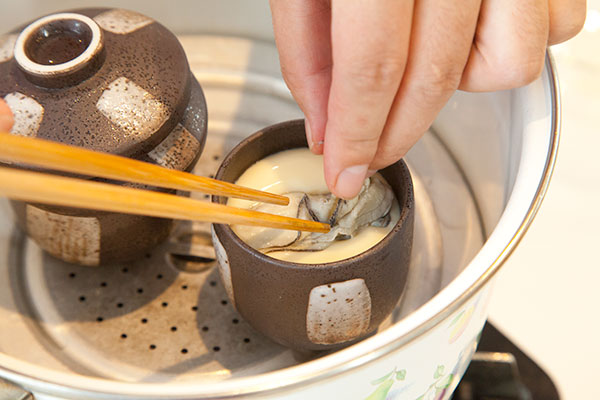 牡蠣の茶碗蒸し7　3分経ったら蓋を開け表面が薄くまくが張っているのを確認し、その上に牡蠣(かき)を乗せます。